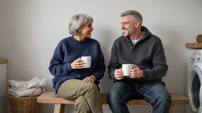 Two friends sit together on a bench in a utility room with a plain mug