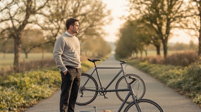 A man stands beside a bicycle in a quiet lane holding an apple
